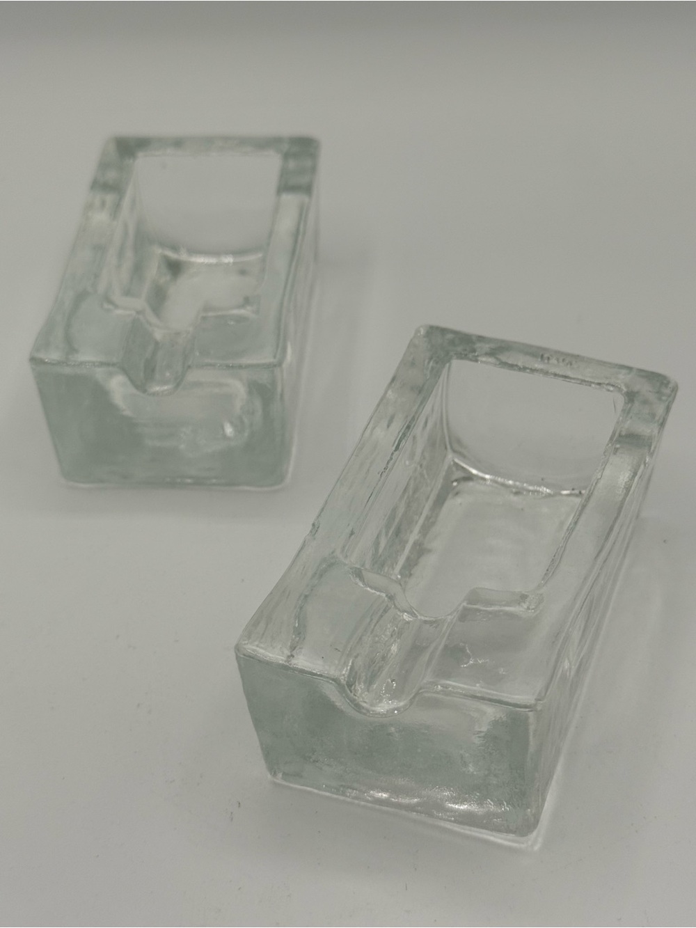 A pair of clear glass 'ice block' design individual ashtrays, etched 'Italy'.